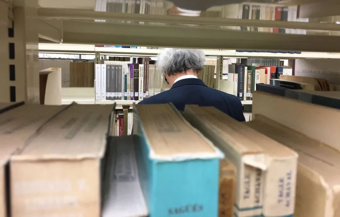Profesor consulta libros en los estantes de la biblioteca