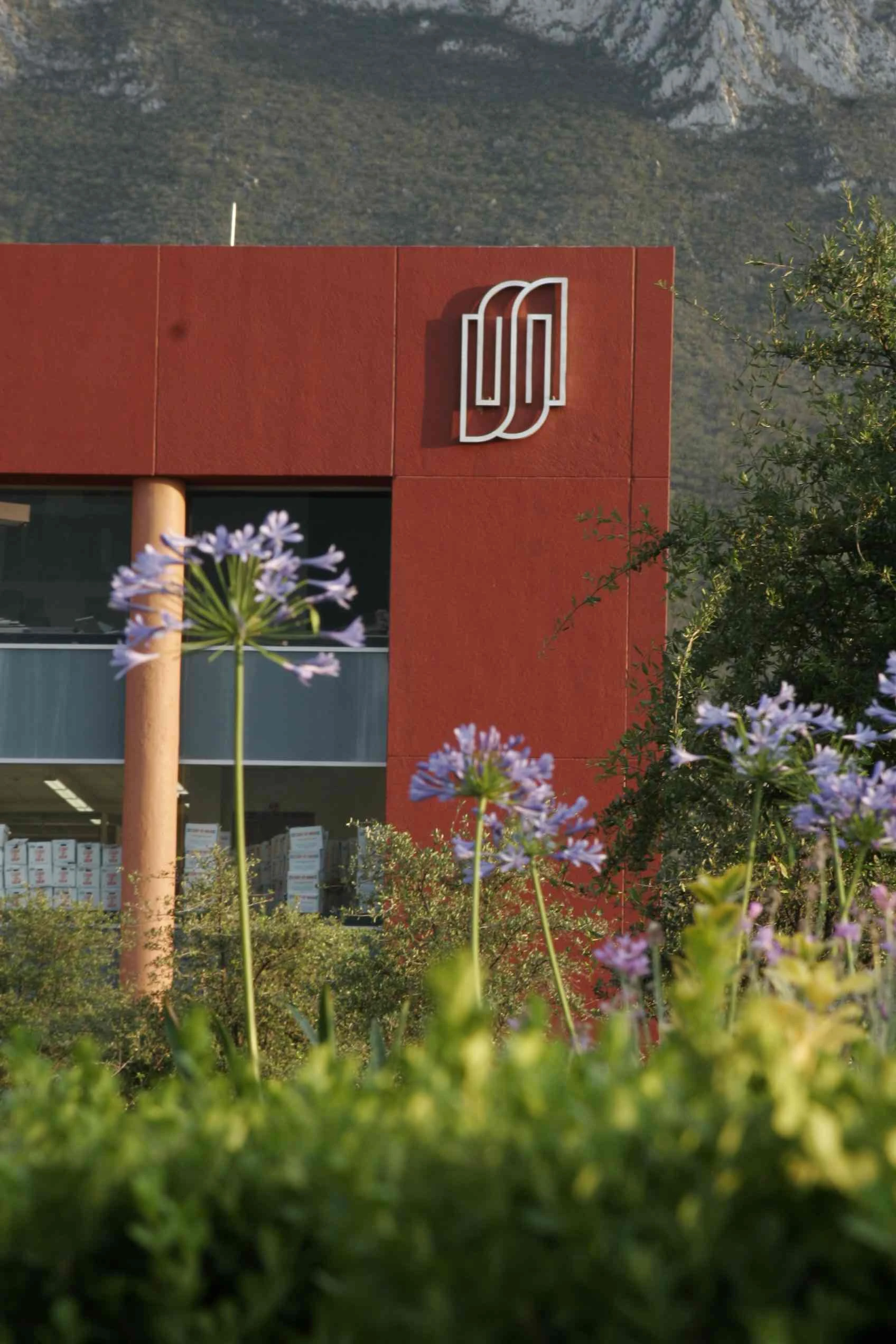 Logotipo de la Facultad Libre de Derecho de Monterrey en la fachada del edificio, enmarcado por flores moradas
